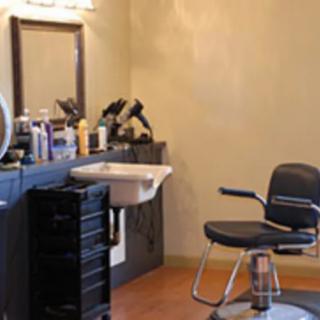 Interior of a hair salon featuring a styling chair, sink, and beauty products.