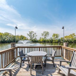 A peaceful deck with wooden seating overlooking a lake with fountains.
