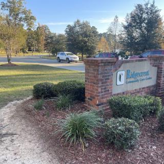 A welcoming entry sign for a community, surrounded by lush greenery and a clear sky.