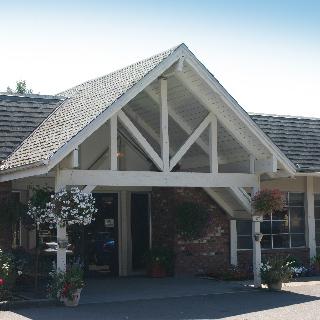 A charming entrance featuring a peaked roof and inviting landscaping.