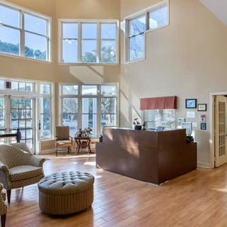 A spacious and modern reception area with large windows allowing ample natural light, featuring comfortable seating and a sleek wooden reception desk.
