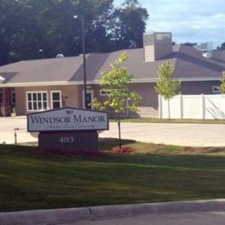 A view of a building with a sign reading 'Windsor Manor' and a well-maintained lawn in the foreground.