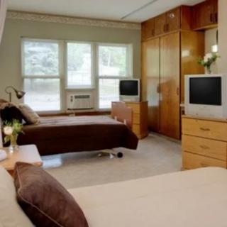 A modern bedroom with two beds, wooden furniture, and televisions in front of each bed.