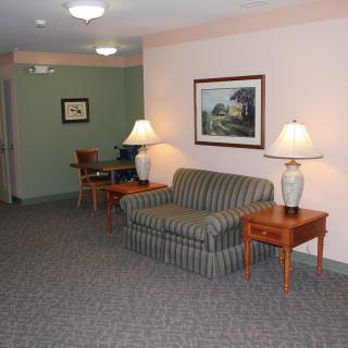 A cozy waiting area with a striped sofa, side tables with lamps, and wall paintings.