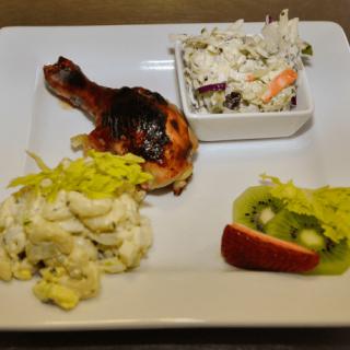 A meal featuring chicken, salad, and fruit on a plate.