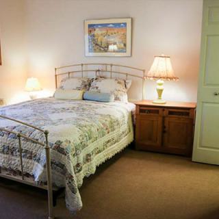 A cozy bedroom with a neatly made bed, bedside lamps, and warm decor.