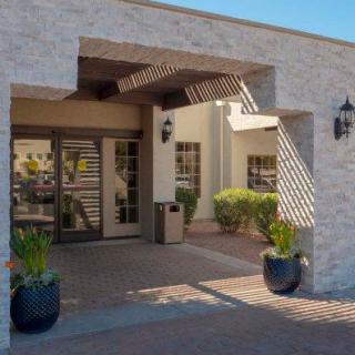 Entrance to a modern building with glass doors and potted plants.