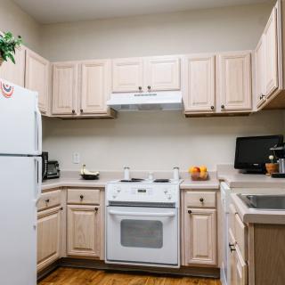 A cozy kitchen with light wood cabinets, a white stove and refrigerator, and a small countertop workspace.