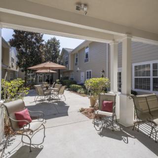 A cozy outdoor patio with seating arrangements and a sun umbrella, perfect for relaxing on a sunny day.