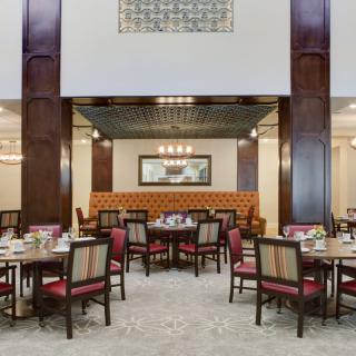 A spacious and elegantly decorated dining room featuring multiple tables and chairs, with a warm and inviting ambiance.