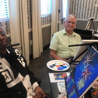 Two seniors enjoying a painting session together.
