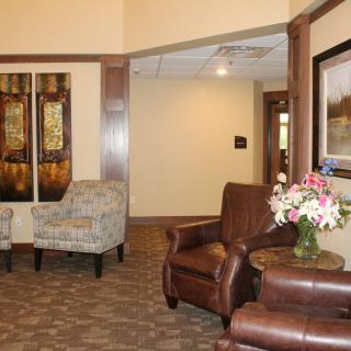 A cozy lobby area with armchairs, a painting, and a flower arrangement.