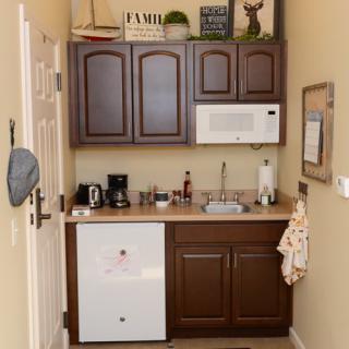 A compact kitchen area with a microwave, coffee maker, and wooden cabinets.