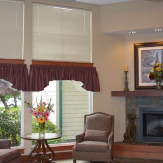 A cozy living room with elegant window treatments, comfortable armchairs, and a decorated fireplace.