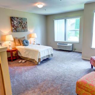 A cozy bedroom with a bed, lamps, and bright natural light coming through the window.