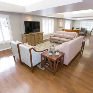 A modern living room with a comfortable sofa set, wood flooring, and a flat-screen television.