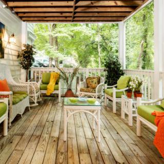 A cozy porch with vibrant seating and lush greenery.