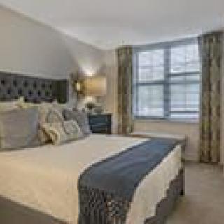 A cozy and modern bedroom with an elegant bed, stylish curtains, and a large window providing ample natural light.