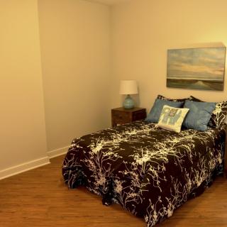 A cozy and modern bedroom featuring a bed with decorative pillows, a bedside lamp, and wall art.