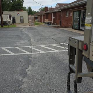 A view of a quiet parking lot with faded street markings and nearby buildings.