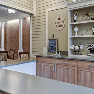 A cozy cafe interior with a wooden counter and decorative shelves, featuring a small seating area.