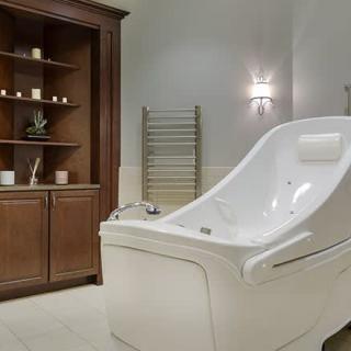 A luxurious spa bathroom featuring an elegant white bathtub with a wooden cabinet for storage.