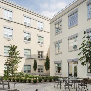 A serene courtyard with tables and chairs surrounded by a modern building.