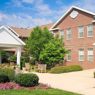 A brick residential building with a well-maintained garden and driveway.