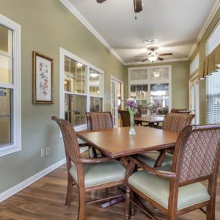 A well-lit dining room with a wooden table, chairs, and ceiling fan.