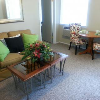 A cozy living room with a sofa, coffee table, and dining area.