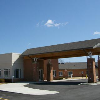 A modern building entrance with a covered driveway under a clear blue sky.
