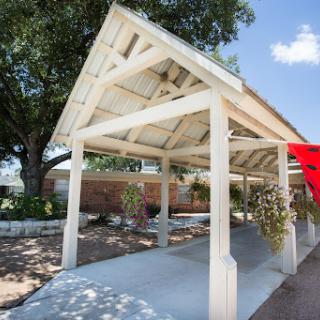 A beautifully designed outdoor pavilion with a white wooden structure, set against a sunny sky.