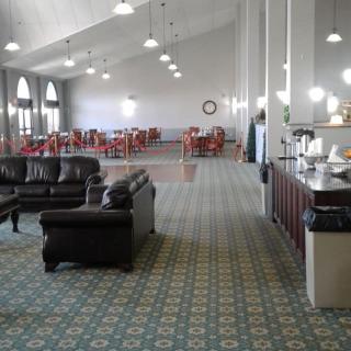 Spacious lounge area with sofas, armchairs, and tables under warm lighting.