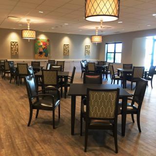 A modern dining room with neatly arranged tables and chairs, featuring stylish lighting and decor.
