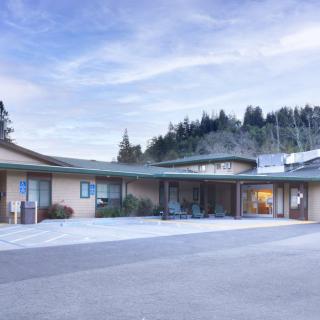 A single-story building surrounded by trees with a clear sky overhead.