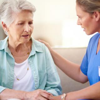 A nurse providing support and care to an elderly woman.
