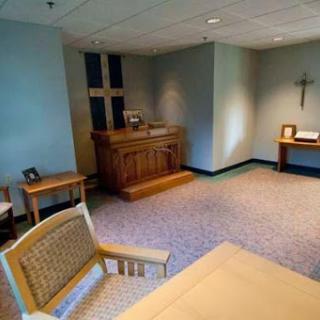 A serene interior of a chapel featuring wooden furnishings and a cross.