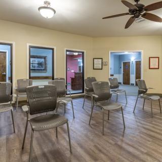 An office waiting room featuring rows of chairs and a ceiling fan.