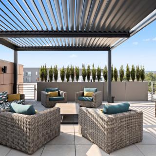A modern outdoor terrace featuring comfortable patio furniture and a sleek pergola.