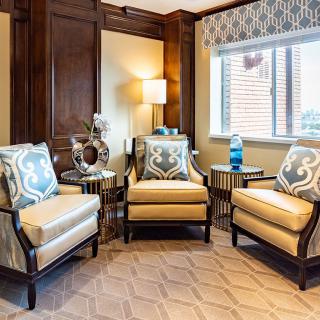 A cozy living room featuring three stylish armchairs, a lamp, and decorative accents.