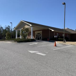 A view of a commercial building with an empty parking lot on a clear day.