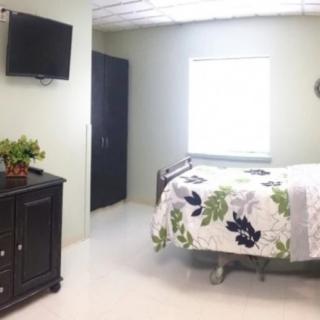 A modern, minimalist bedroom with a bed, wall-mounted TV, and simple furnishings.