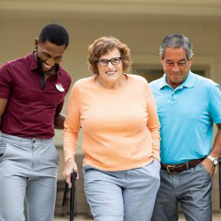 A joyful moment as caregivers assist an elderly woman while walking outdoors.
