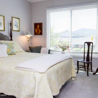 A cozy bedroom with elegant decor and a large window allowing natural light.