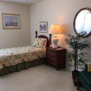 A cozy bedroom with a single bed, nightstand, lamp, and decorative elements.