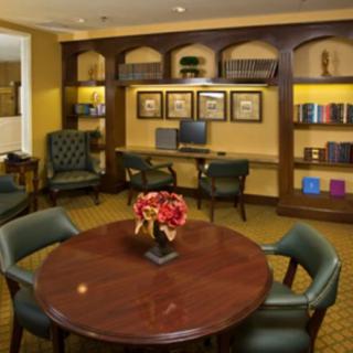 A cozy library room with a round table, chairs, and bookshelves lining the walls.