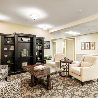 A cozy living room with plush seating, a dark wood bookshelf, and a patterned carpet.