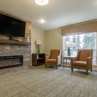 A cozy living room with armchairs, a fireplace, and a large television.