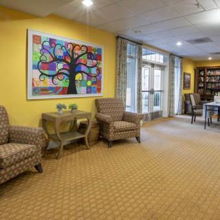 A cozy lobby area with armchairs, colorful artwork on yellow walls, and large windows providing natural light.