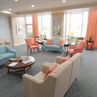 A cozy and elegantly designed living room with pastel-colored furniture and large windows.